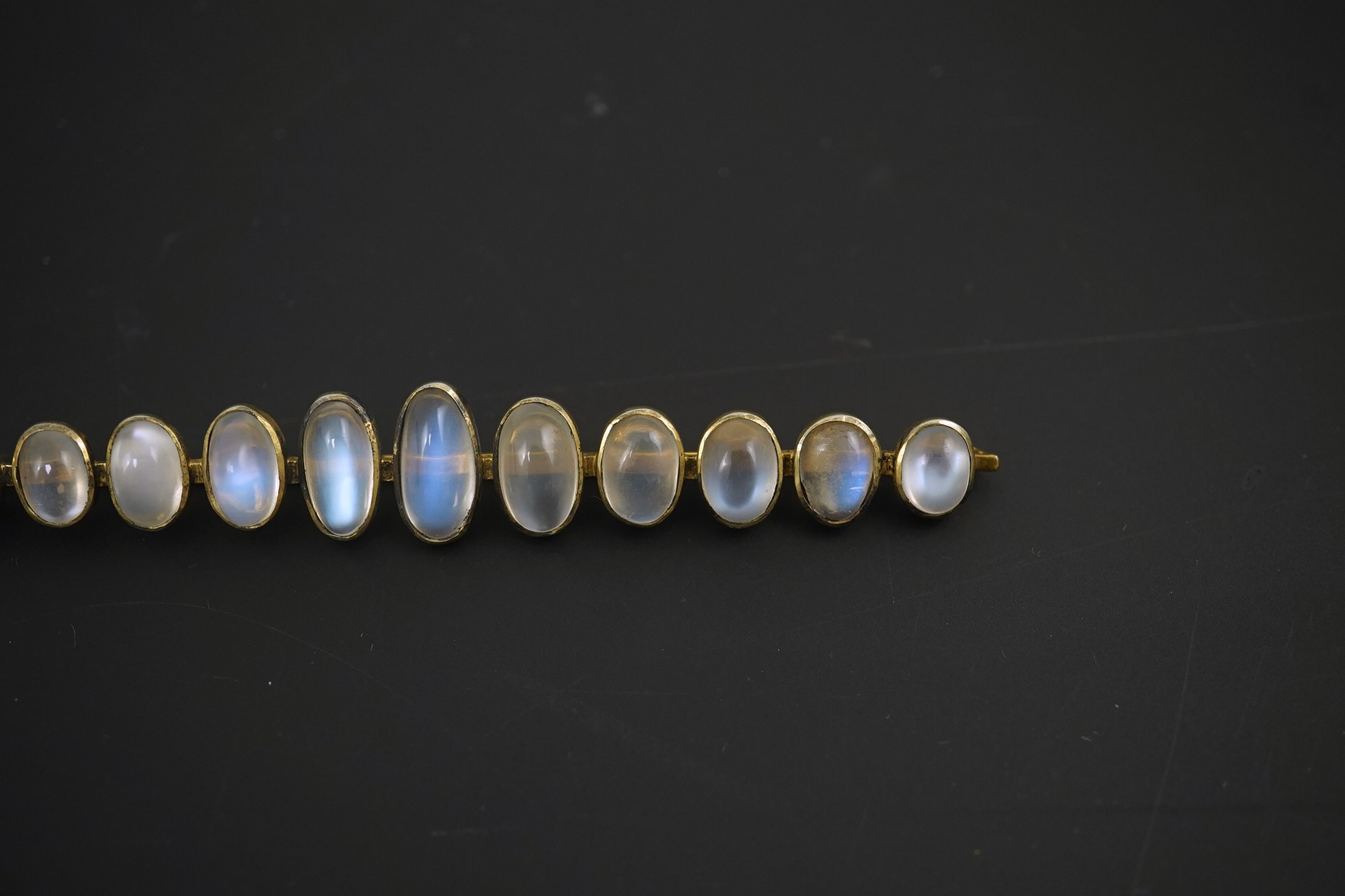 A gold and eleven stone graduated cabochon moonstone set bar brooch